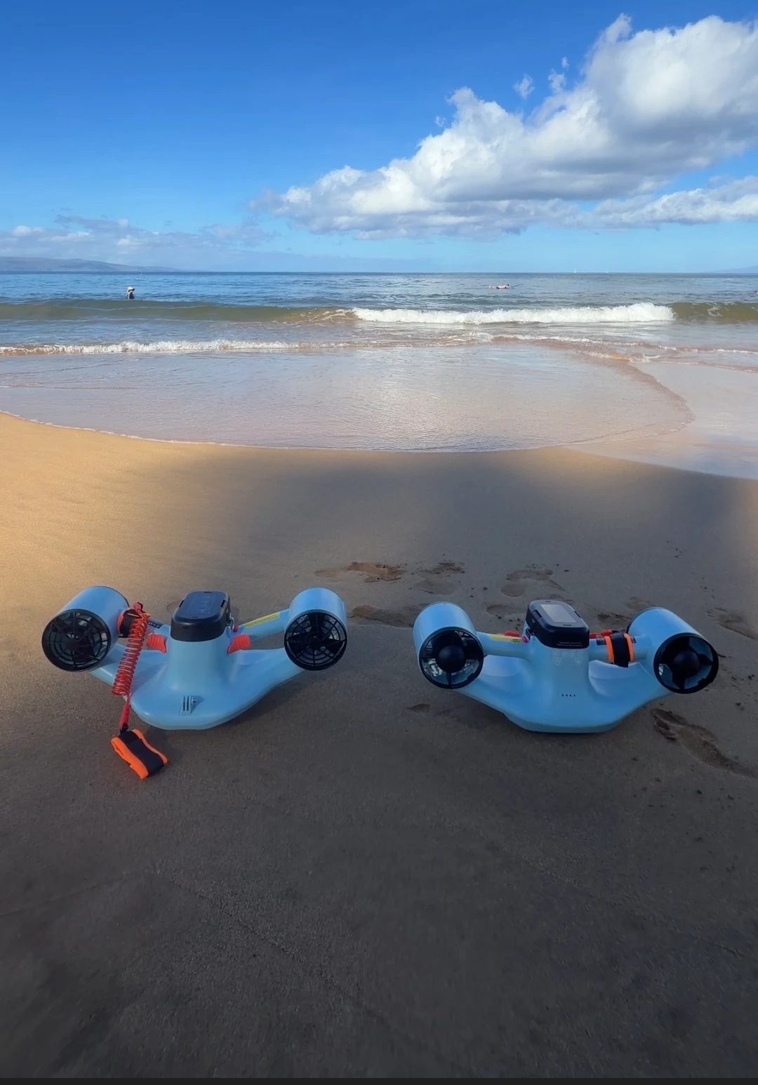 Two sea scooters on a Maui beach with ocean and sky in the background